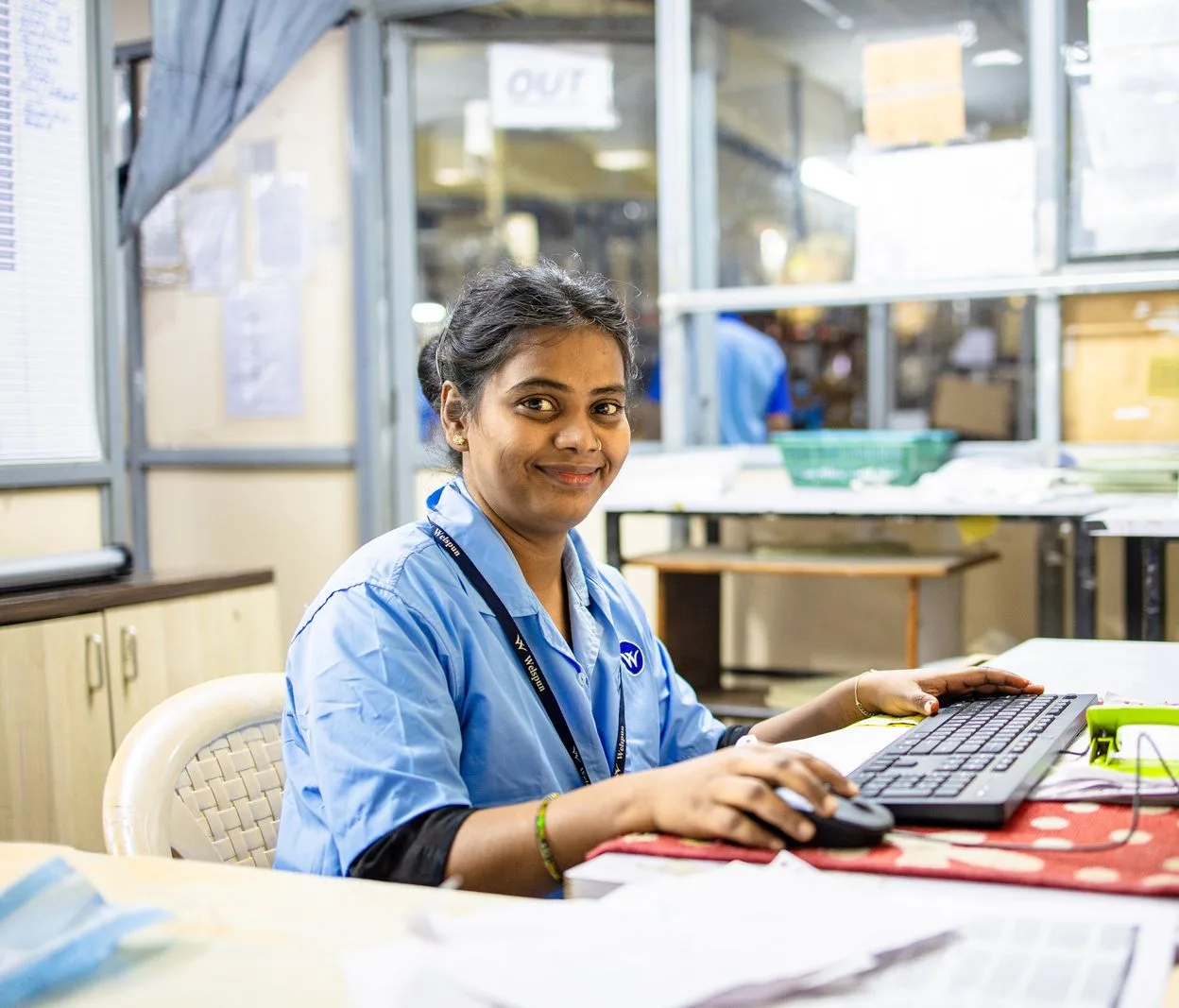 A receptionist in a blue uniform at a registration desk computer in India.