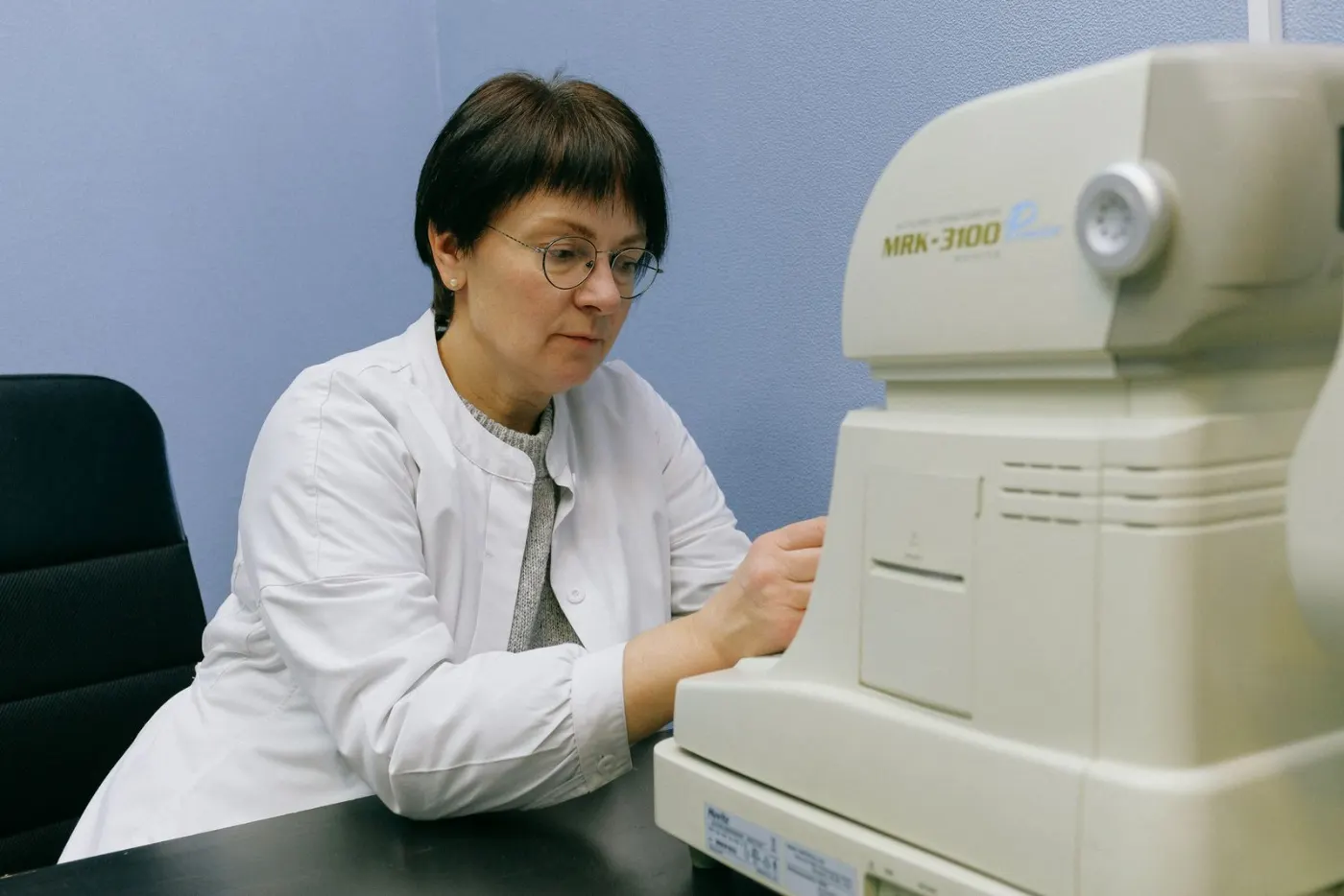 An eye specialist using an automated eye-testing instrument with a patient