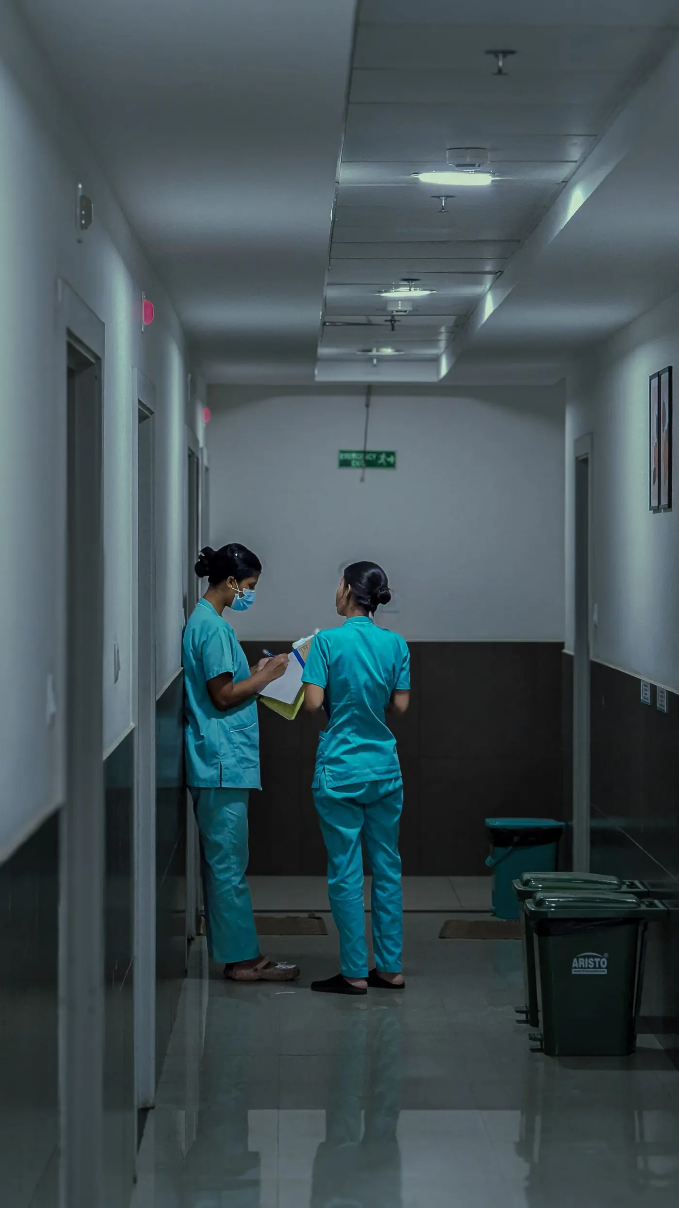 Two nurses going over patient notes in a hospital corridor in India.