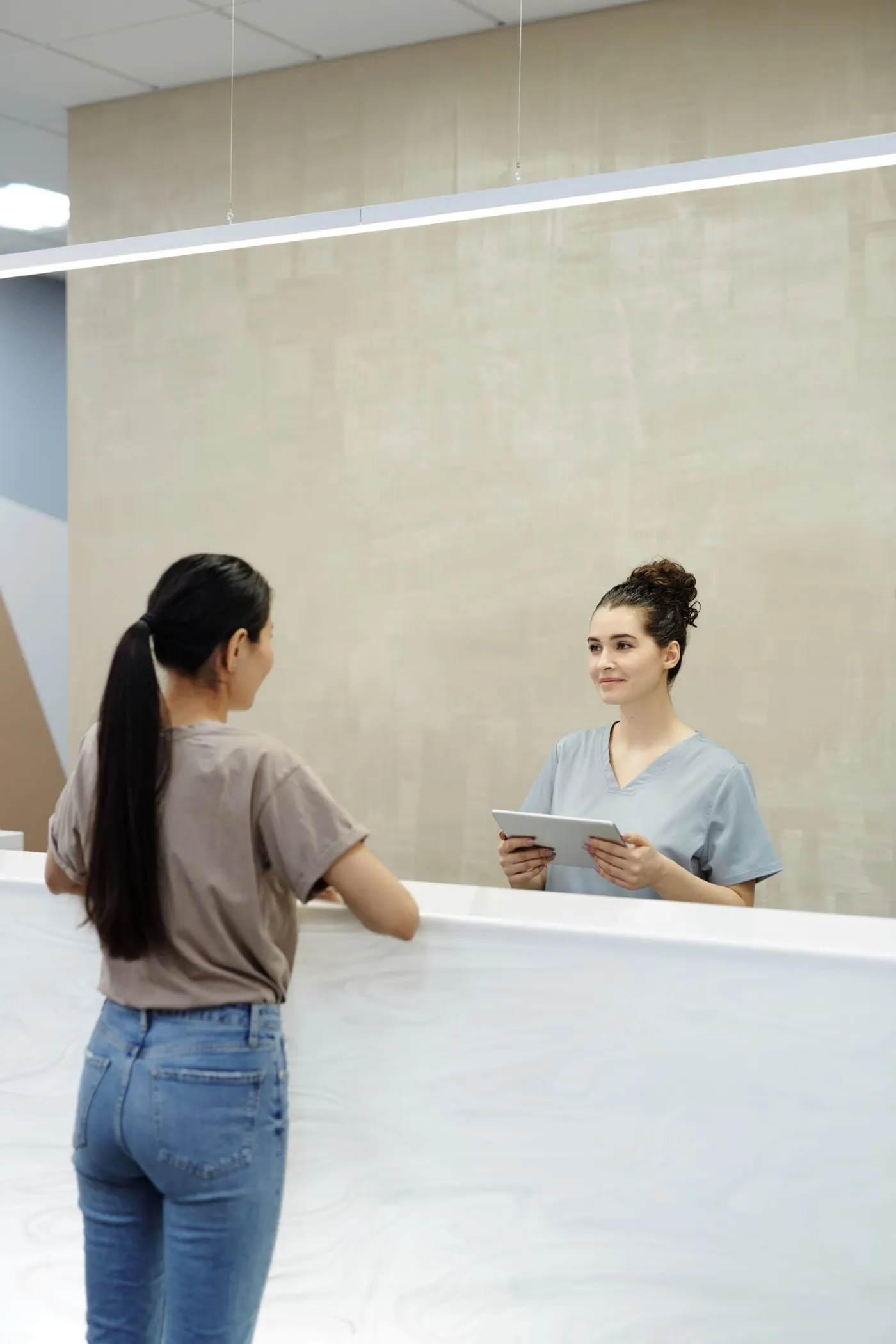 A hospital receptionist using a tablet at the front desk