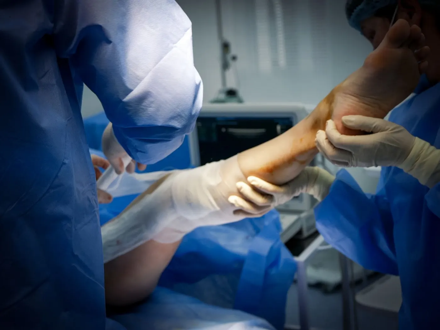 A surgical team operating on a patient's leg in an operating room.
